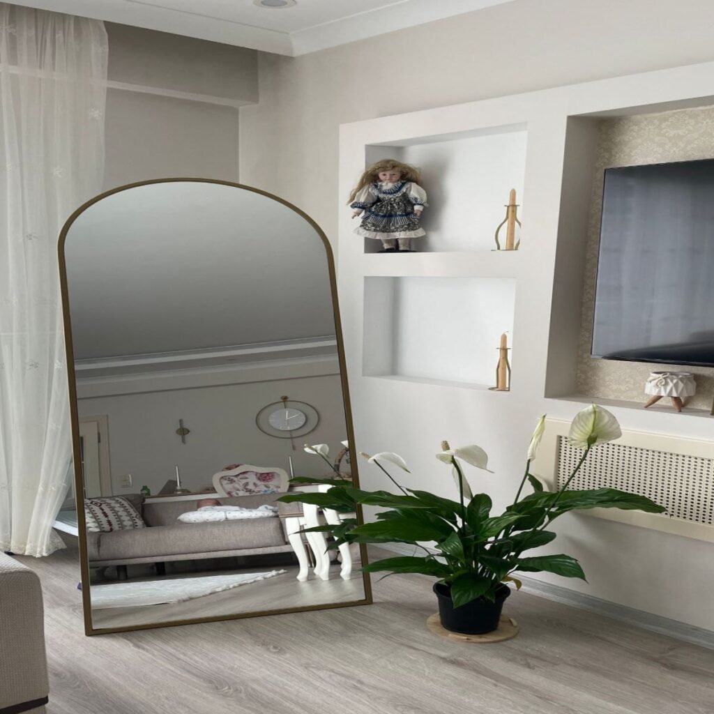 Modern bedroom decor with a full-length mirror reflecting natural light and simple neutral decor
