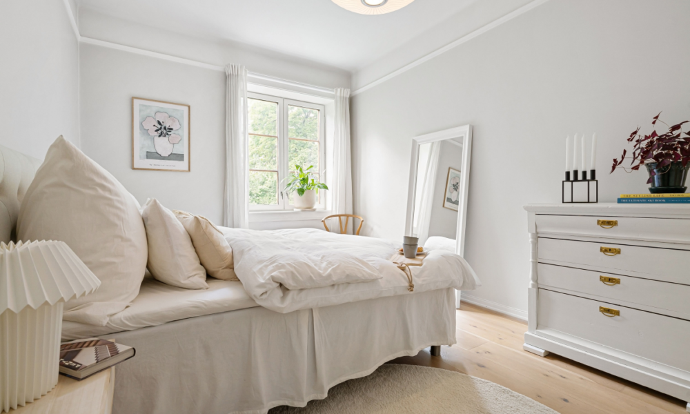 elegant minimal rental friendly small bedroom with white bedding plants and natural light