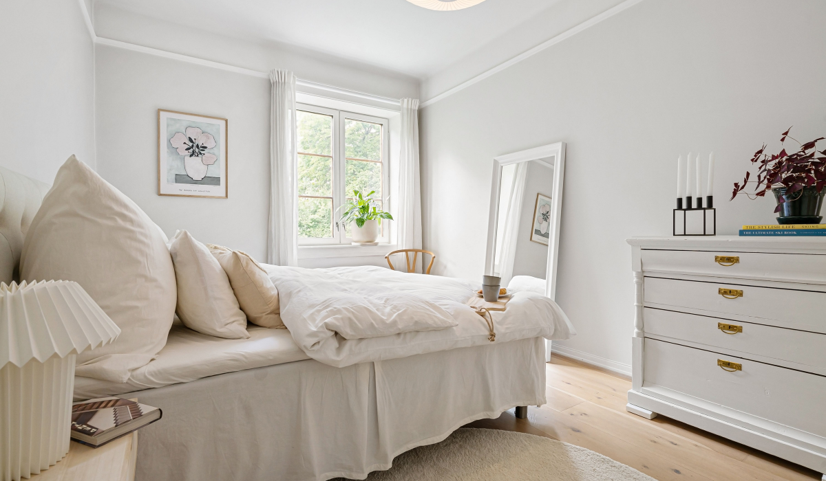 elegant minimal rental friendly small bedroom with white bedding plants and natural light